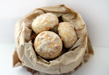 Biscuits in a paper bag on a white background. Stuffed gingerbread cakes covered with sugar glaze on top.