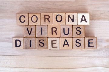 The inscription corona virus disease on a wooden background, top view. The epidemic of the covid-19 virus. Wooden cubes with letters.