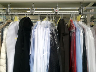 Weiße Hemden und andere Kleidungsstücke auf der Kleiderstange in Plastikfolie in einer Reinigung...
