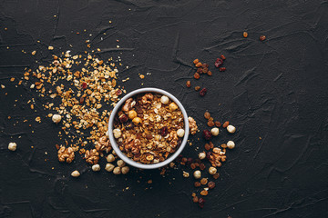 a delicious and crunchy oatmeal granola with honey, nuts, dried fruits and grains is poured out of the praml package into a plate.  food photography background
