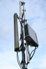 Cellular radio telecommunication network antenna mounted on a metal pole providing strong signal waves from the top of the roof across big city 