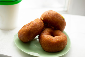 Three delicious donuts on a green saucer.