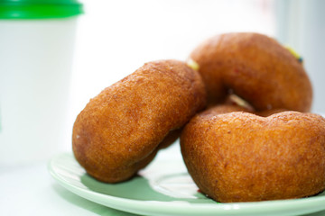 Three delicious donuts on a green saucer.