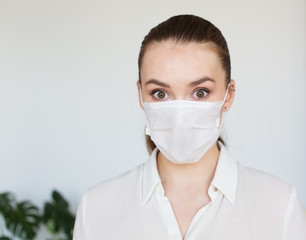 COVID-19 Pandemic Coronavirus Young girl in white room wearing face mask protective for spreading of Coronavirus Disease 2019. Close up of young woman with surgical mask on face against SARS-CoV-2.