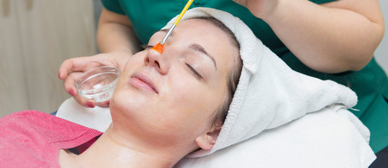 Face skin care. Beautician applying beauty oil mask on face using brush In spa salon