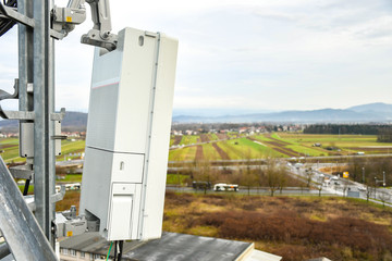 5G new radio telecommunication network antenna mounted on a metal pole providing strong signal waves from the top of the roof across big city 