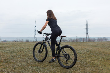 Girl on a mountain bike on offroad, beautiful portrait of a cyclist in rainy weather, Fitness girl rides a modern carbon fiber mountain bike in sportswear. Close-up portrait of a girl in red bandana.