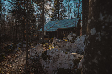 Old army barracks or cottages hiding in the depths of forest at Kocevje or Kocevski rog. Partisan hideout in Slovenia called Baza 20 on a sunny winter day. Visible two of cabins.