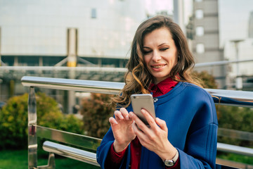 Office buildings city people in suit. Caucasian businesswoman using smartphone with hand. Business concept. Portrait stylish business woman in fashionable clothes holding Phone near office building