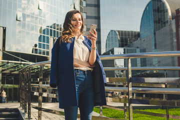 Office buildings city people in suit. Caucasian businesswoman using smartphone with hand. Business concept. Portrait stylish business woman in fashionable clothes holding Phone near office building