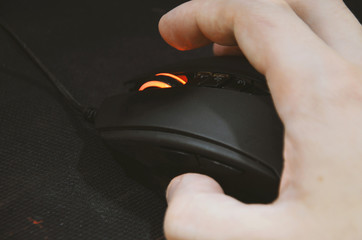 Working at the computer in the office with the mouse. Gaming mouse with red backlight on a black...