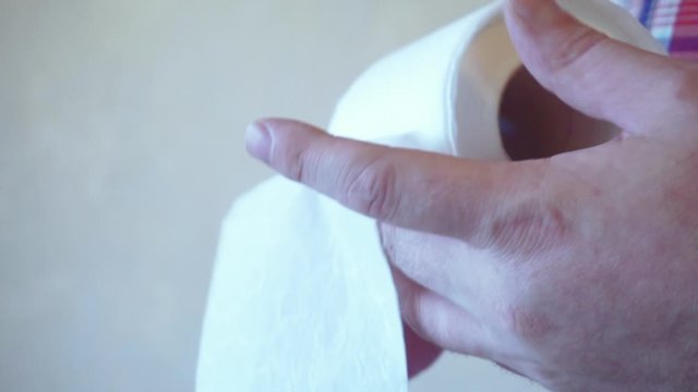 male hands hold a roll of white toilet paper.