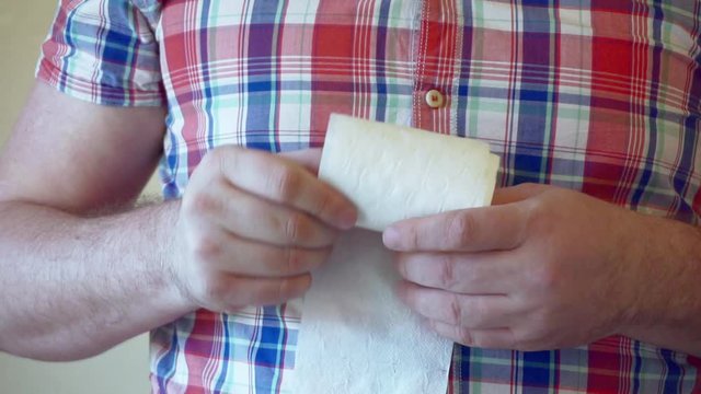 male hands hold a roll of white toilet paper.