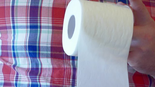 Men's hands unwind a roll of white toilet paper