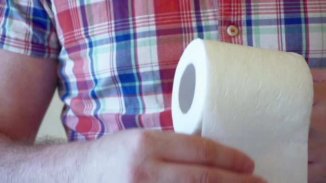 male hands hold a roll of white toilet paper