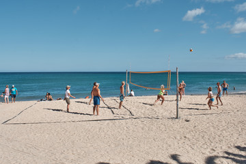 people playing volleyball on the beach on a sunny day