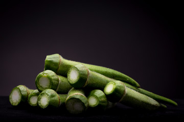Lot of Okra or Ladies' fingers vegetable in graphic moody frame. Studio low key still life of edible food in spotlight contrasted against a dark background