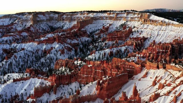 Beautiful morning aerial drone view of the famous Cathedral in Bryce Canyon National Park, Utah. Gorgeous natural red rocks in pillar formations with white snow covering them creating contrast.