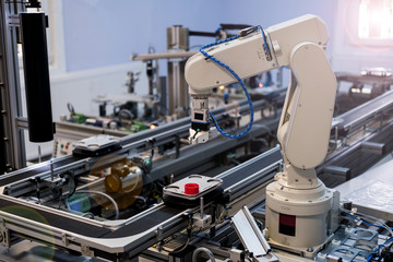 Industry 4.0 smart factory concept; artificial intelligence in production. Close up of robot arm which picks up the product from automated car to process it on station. Selective focus.