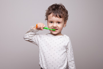 a little boy of three years old is brushing his teeth in the studio on a white background. daily hygiene procedures. healthy and strong Desna, lack of caries.