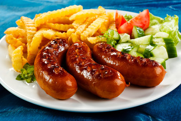 Grilled sausages, French fries and vegetables