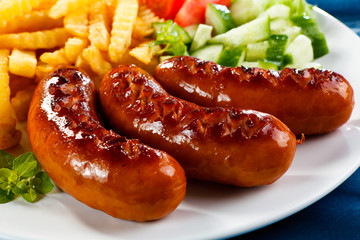 Grilled sausages, French fries and vegetables