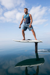 Man riding an electric hydrofoil foil board on a lake with a life jacket