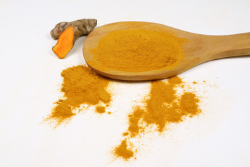 Turmeric powder in a wooden spoon and fresh turmeric roots isolated on a white background is an ingredient in turmeric foods and ingredients in skin care products. Turmeric helps the skin to be strong