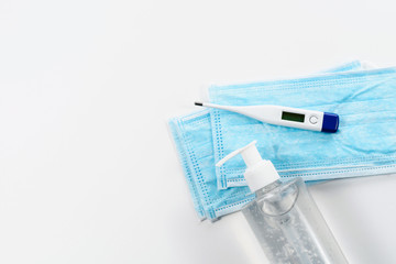 Covid-19. Thermometer, bottle of sanitizer gel and medical mask at white medical table. Treatment...