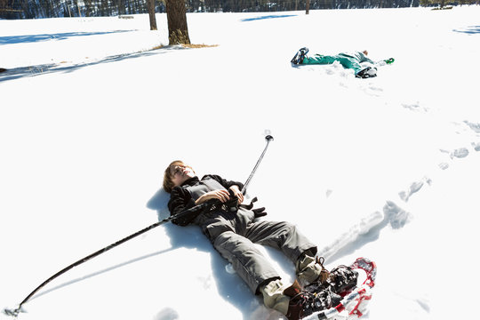 A six year old boy wearing snow shoes, lying down on his back in snow,Valle Caldrea