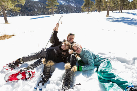 A woman and her two children, teenage girl and a young boy lying in the snow in snow shoes and ski gear. ,Valle Caldrea