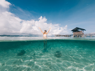Young blonde with raised hands standing on sea shallow