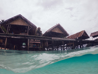 Split shot of picturesque exotic oceania resort for recreation vacation on Raja Ampat, idyllic view of touristic lagoon with crystal waterline for discovering tropical seashore and aquatic life