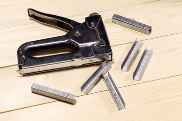 Building metal stapler with staples on a wooden table.