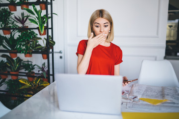 Businesswoman in casual wear puzzling while reading news on laptop at office