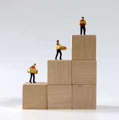 Miniature courier drivers standing on stair-shaped wooden blocks.