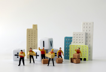 Miniature couriers standing in front of miniature buildings and white cubes with an arithmetic...