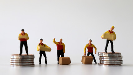 Miniature couriers standing with pile of coins.
