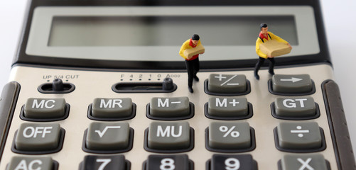 Two miniature couriers standing on a calculator.