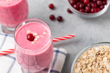Two glasses with freshly homemade smoothie of yogurt, oatmeal and cranberries on a gray table. Healthy eating concept