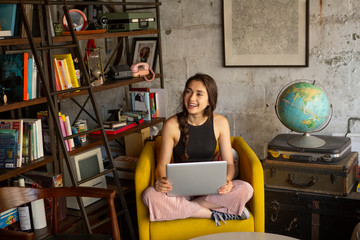 Smiling businesswoman with laptop computer looking away while sitting on armchair at creative office © Cavan for Adobe