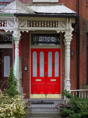 old house with wooden porch railings and bright red front  door