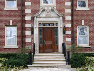 Large brick house with elegant wooden door surrounded by elaborate stone frame