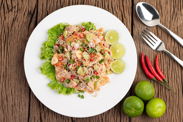 Spicy pork salad with galangal, lemon, chilli, garlic and put in a salad on a white plate.