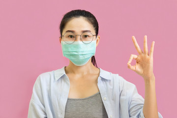 Young asian woman worea gray tank top, Blue shirt and protective masks against virus and air pollution,make gesture Coughing, isolated on pink background