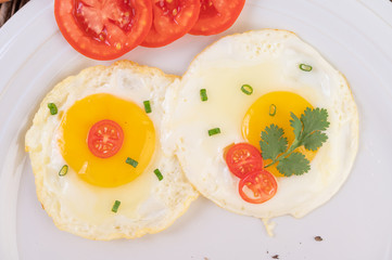 Fried egg on a white plate with sliced ​​Spring onion and sliced ​​tomatoes