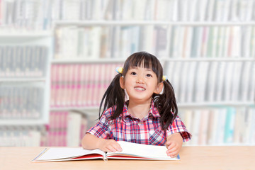 図書館で読書する幼い女の子。読書、勉強、興味、集中イメージ