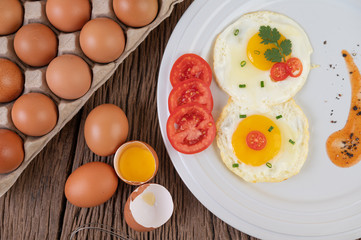 Fried egg on a white plate with sliced ​​Spring onion and sliced ​​tomatoes