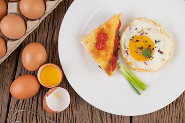 Fried egg on a white plate with sliced ​​Spring onion and sliced ​​tomatoes