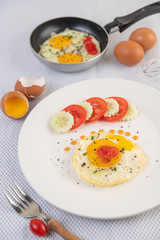 Fried egg on a white plate with sliced ​​Spring onion and sliced ​​tomatoes